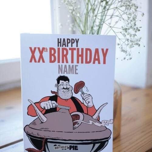 Desperate Dan birthday card featuring 'Happy Xth Birthday' text with space for name and birthday pie illustration displayed on table