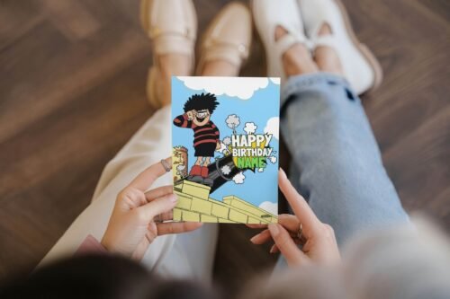 Personalised Dennis menace cannon birthday card template with 'Happy Birthday' text and space for a name, ideal for custom celebrations.