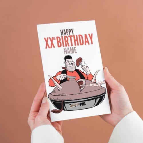 Person holding a Desperate Dan birthday card featuring 'Happy Xth Birthday' text with space for name and birthday pie illustration