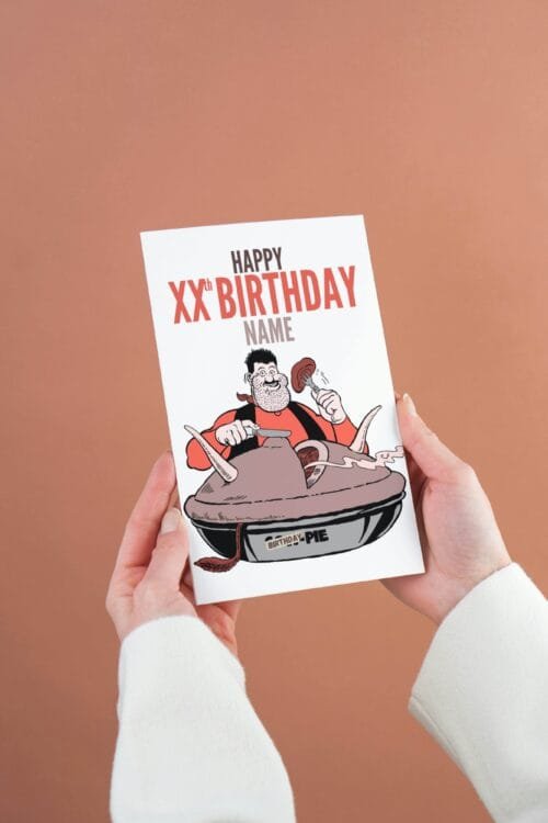 Person holding a Desperate Dan birthday card featuring 'Happy Xth Birthday' text with space for name and birthday pie illustration