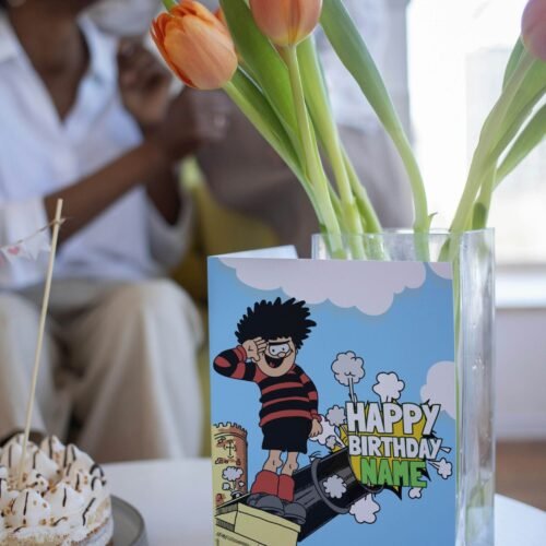 Personalised Dennis menace cannon birthday card template with 'Happy Birthday' text and space for a name, ideal for custom celebrations.