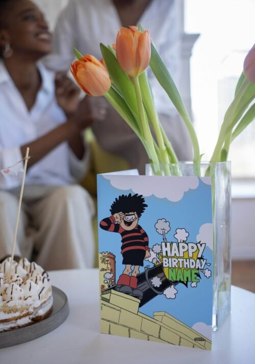 Personalised Dennis menace cannon birthday card template with 'Happy Birthday' text and space for a name, ideal for custom celebrations.