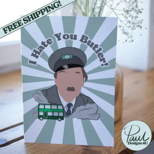 Screenshot of a customizable greeting card featuring the playful quote 'I hate you butler!' in bold, retro-style font, referencing the classic British sitcom On the Buses. The text is set against a plain or lightly textured background, evoking a humorous and nostalgic tone for fans of the show. This features the card upright on a table with a cartoon of character from the show Blake.