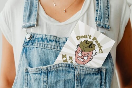 Don’t Panic birthday card peeking out of a denim dungaree pocket for a playful display shot