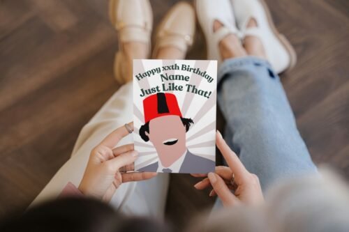 Close-up of hand-drawn Tommy Cooper card being held, showing fez and retro design