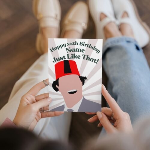 Close-up of hand-drawn Tommy Cooper card being held, showing fez and retro design