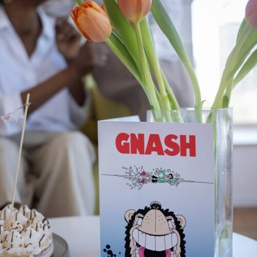 Birthday card with Gnasher and dramatic comic art resting on wooden table