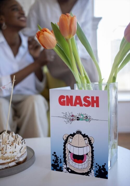 Birthday card with Gnasher and dramatic comic art resting on wooden table
