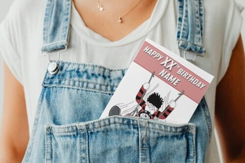 Colourful comic birthday card peeking from denim pocket, with Dennis the Menace design