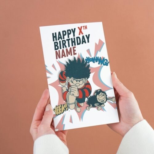 Dennis the Menace and Gnasher personalised birthday card with custom name and age, held in hand