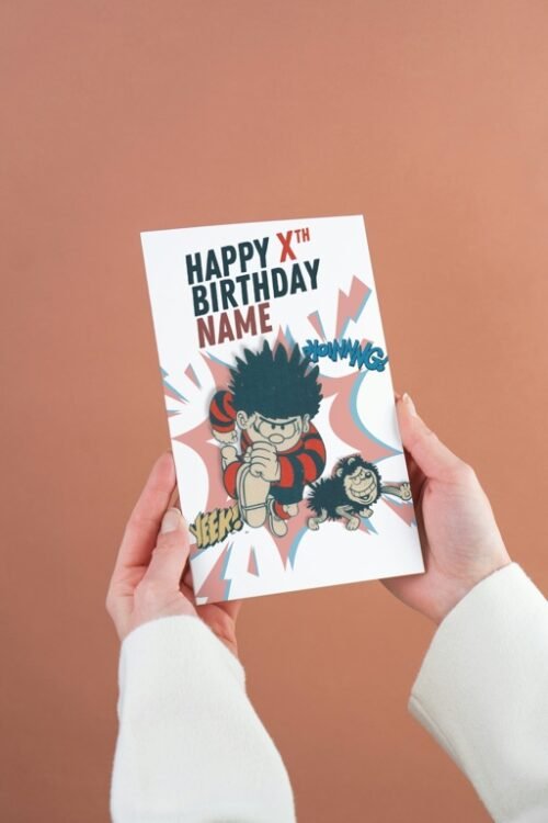 Dennis the Menace and Gnasher personalised birthday card with custom name and age, held in hand
