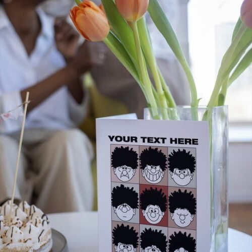 Beano-style greeting card on table featuring Dennis’s funny faces and text space