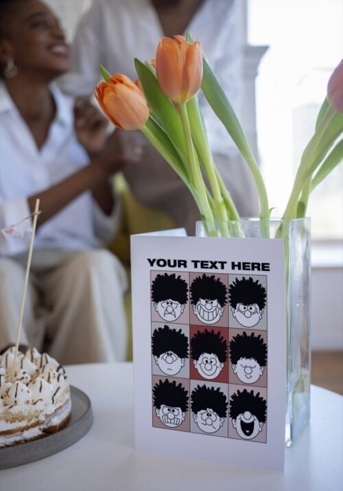 Beano-style greeting card on table featuring Dennis’s funny faces and text space